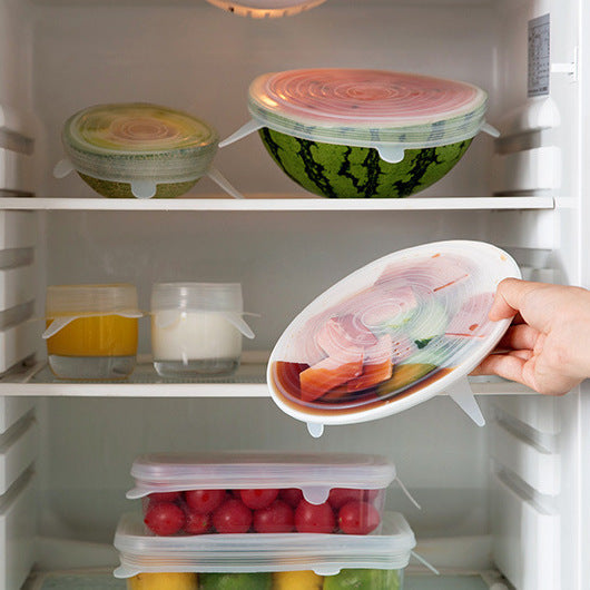 Hand opening a refrigerator door with a container of food inside.