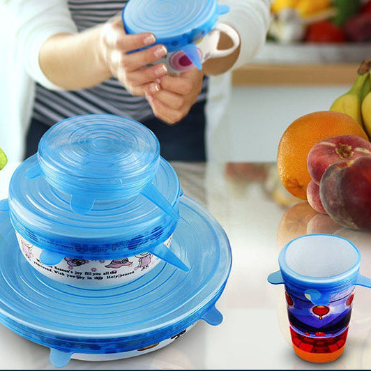 Blue silicone lid on a kitchen counter with colorful cups and fruits in the background