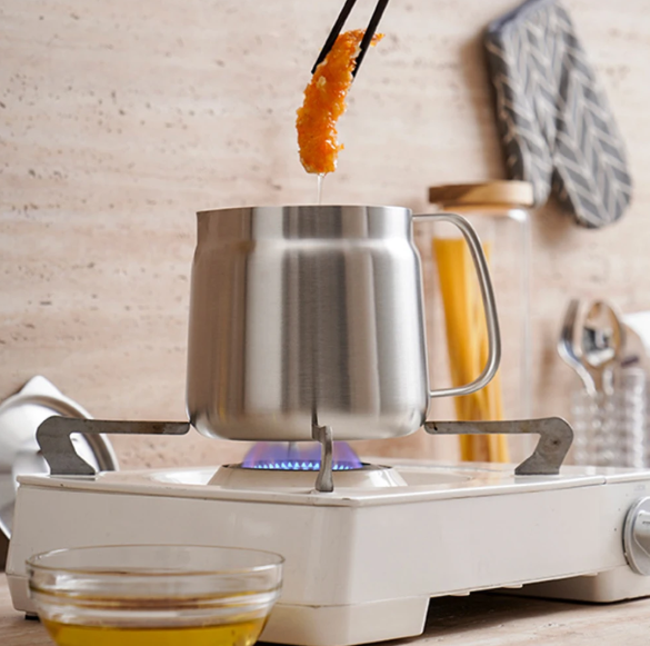 Stir-frying food over a portable stove with a metal pot.